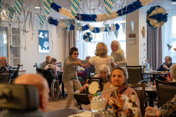 Gruppe von Senionren tanzt in einem Raum, der Oktoberfesttypisch dekoriert ist.